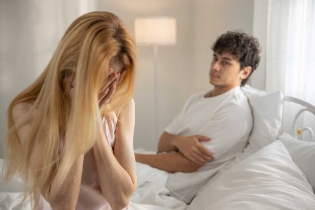 A woman holding her head in distress while a man looks on, illustrating a nervous system response to dating anxiety.