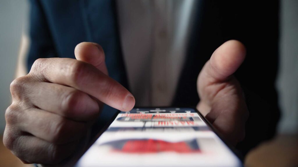 Close-up of a person's thumb scrolling through a social media feed, representing the cycle of social media addiction.