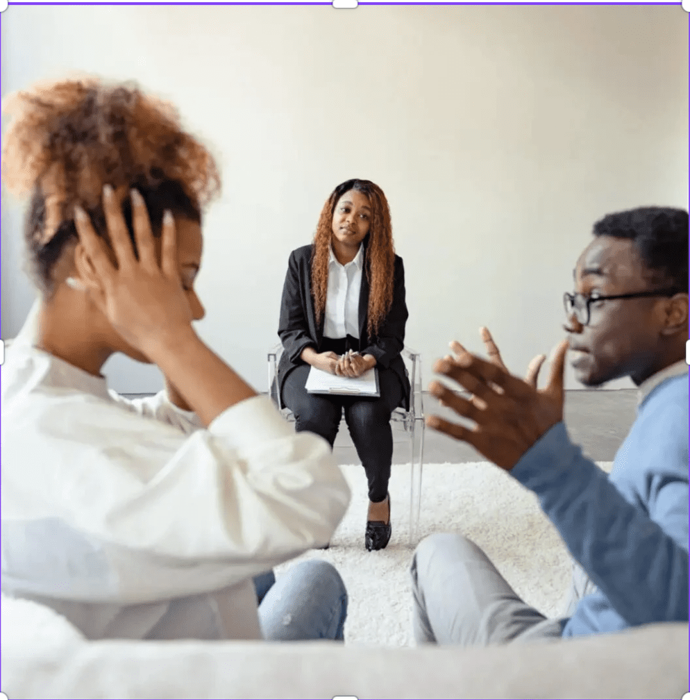 A woman and man sit facing each other, appearing distressed, while another woman with a notepad sits across from them, suggesting a counseling or therapy session.